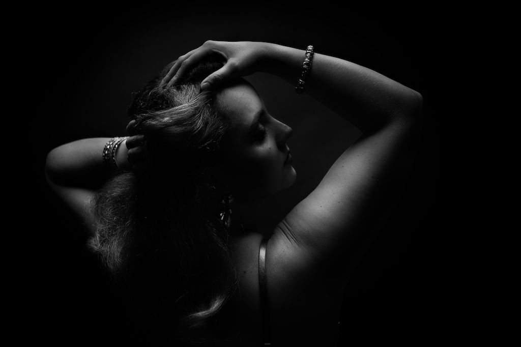 Boudoirshoot: Zwart-wit silhouetportret van een vrouw met haar handen in haar haar, zeewolde