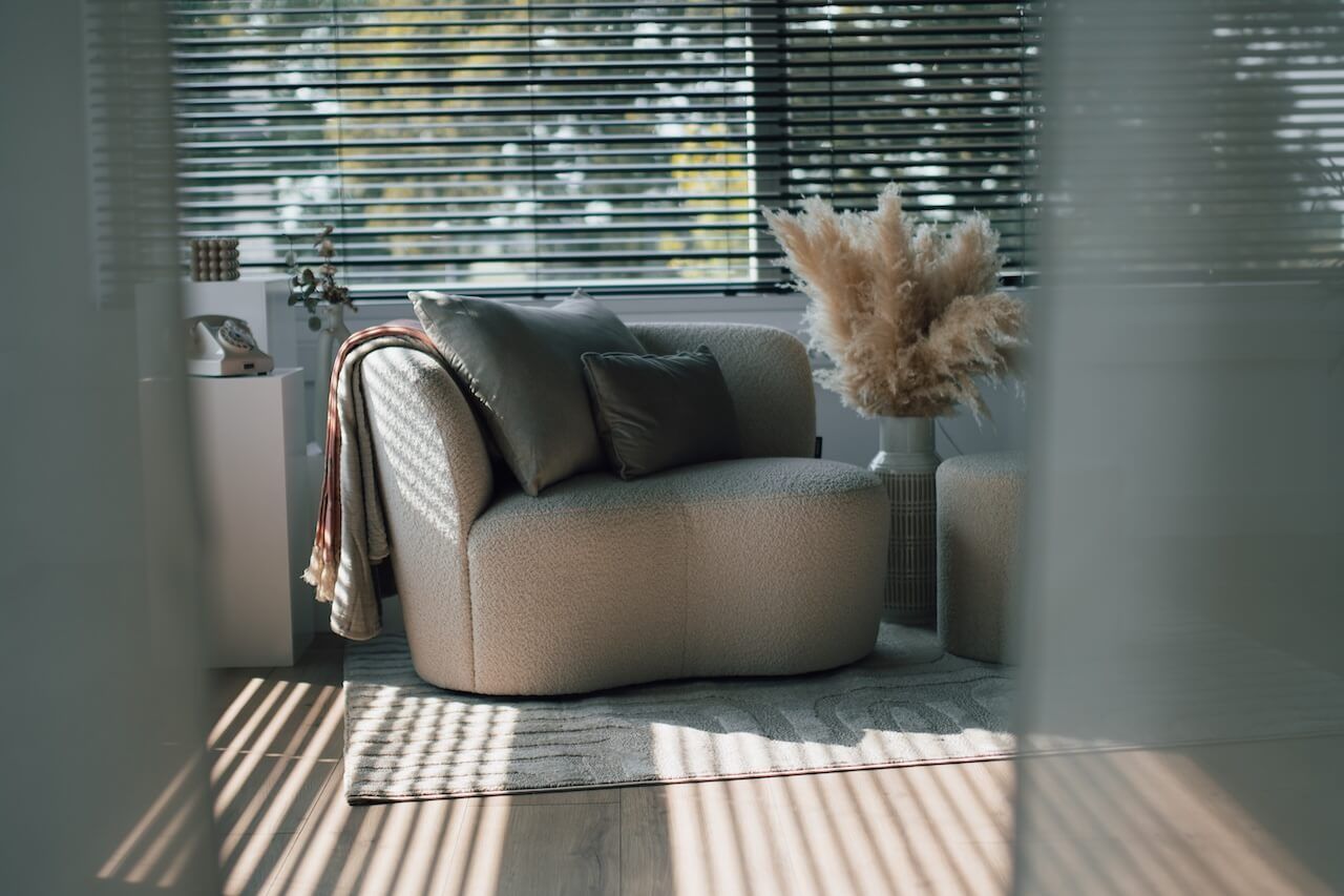 Daglichtstudio Zeewolde met Moderne, gebogen grijze bank met decoratief pampasgras in een zonovergoten kamer