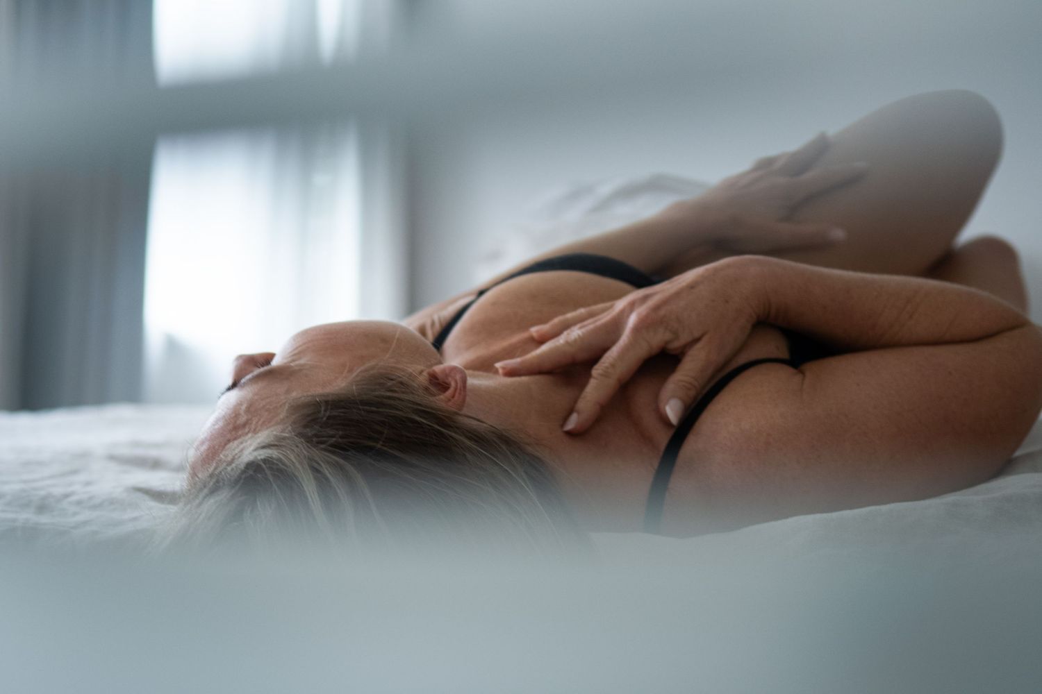Intieme boudoirfoto met zacht dromerig raamlicht.