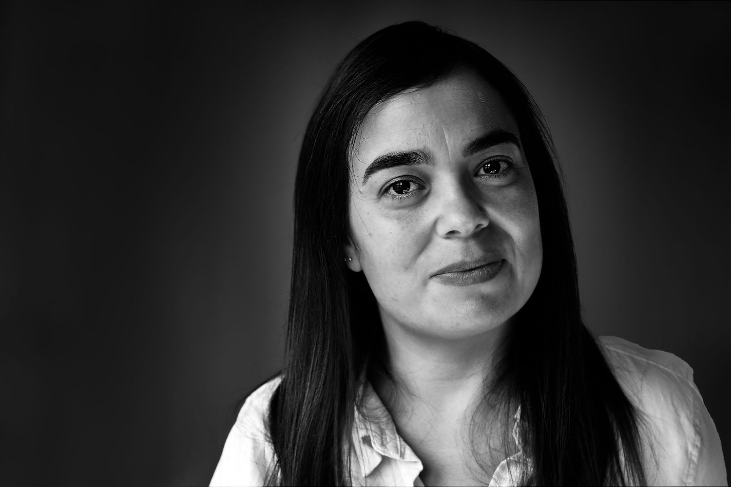 Black and white portrait with dramatic lighting against dark background.