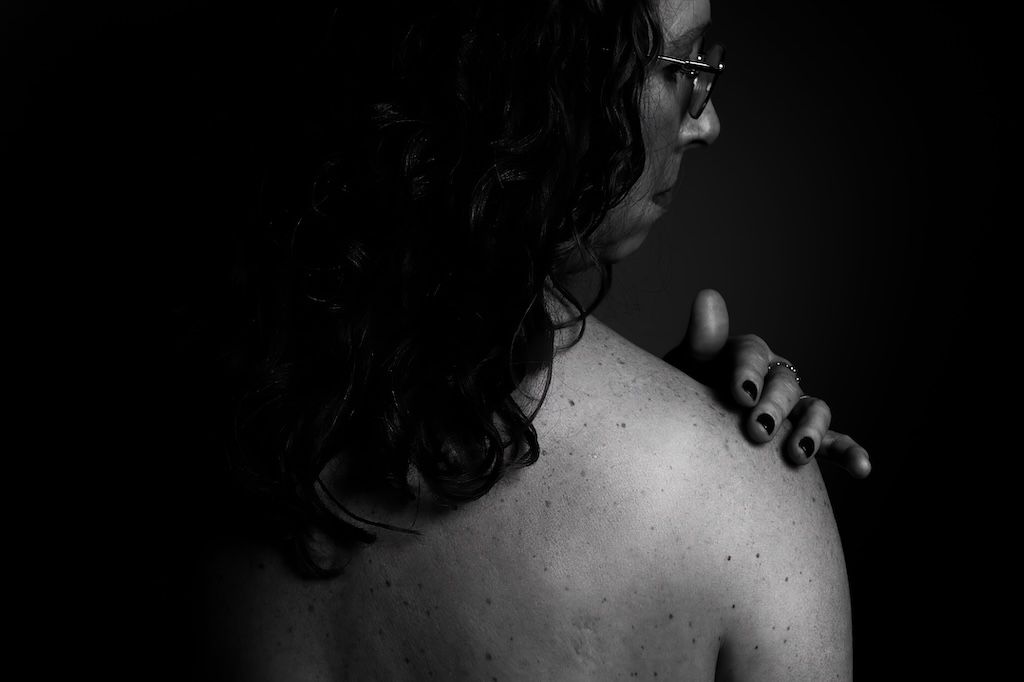 Intieme boudoirfoto van vrouw met hand op blote schouder in Zeewolde
