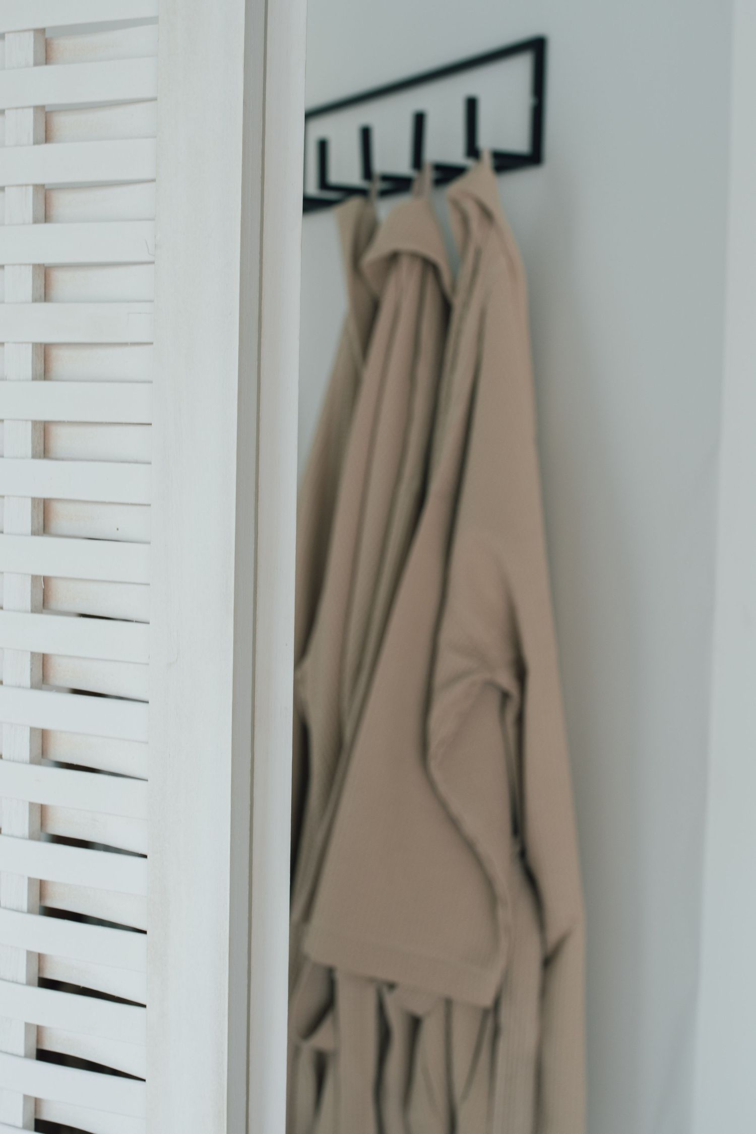 Beige badjassen die aan witte muur hangen in daglichtstudio Zeewolde