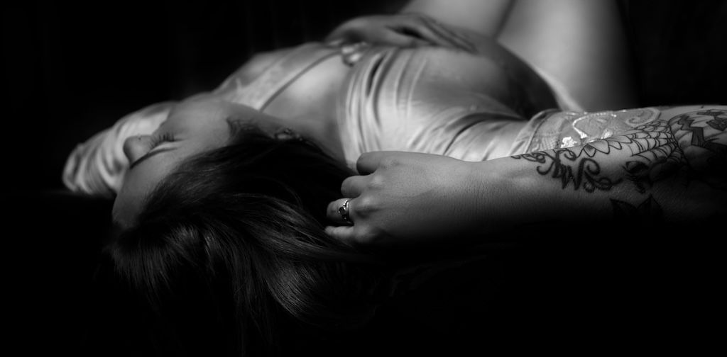 zwart-wit boudoirfoto van een vrouw met een bloementattoo, liggend in Zeewolde