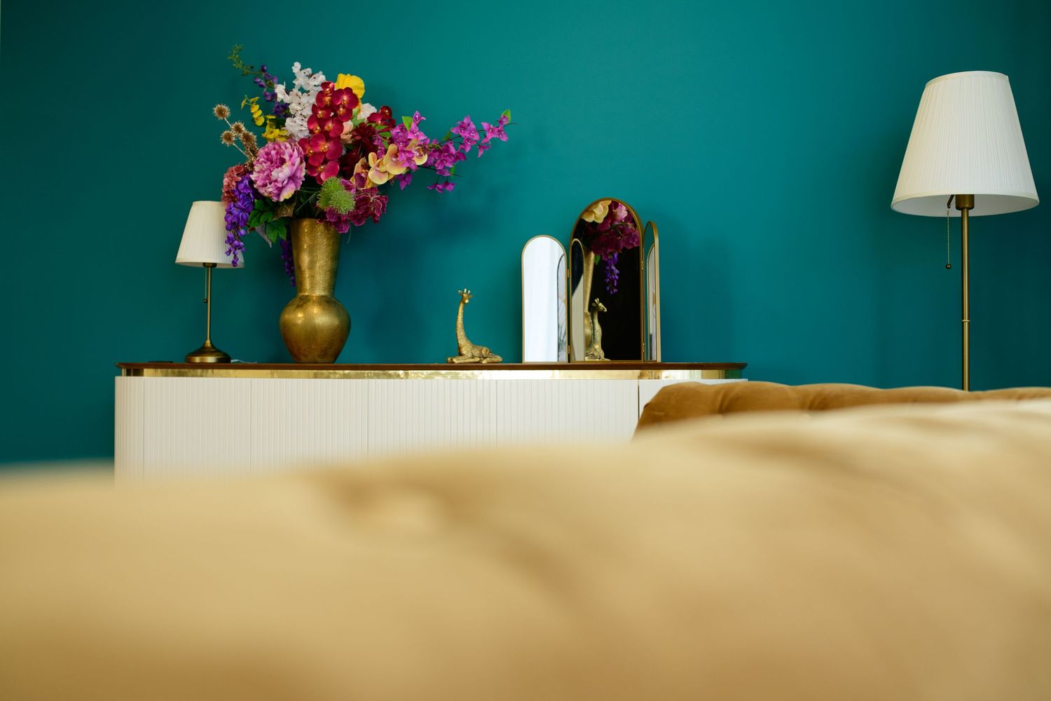 Een accentmuur in een groenblauwe tint in een moderne woonkamer met gouden en witte decoratieve elementen in daglichtstudio Zeewolde