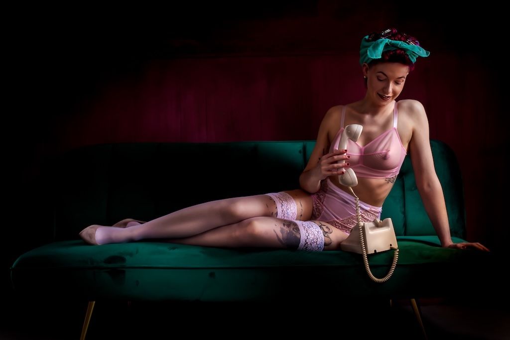 Vintage pin-up boudoir foto op een blauwgroene bank met roze lingerie. Boudoirshoot Zeewolde