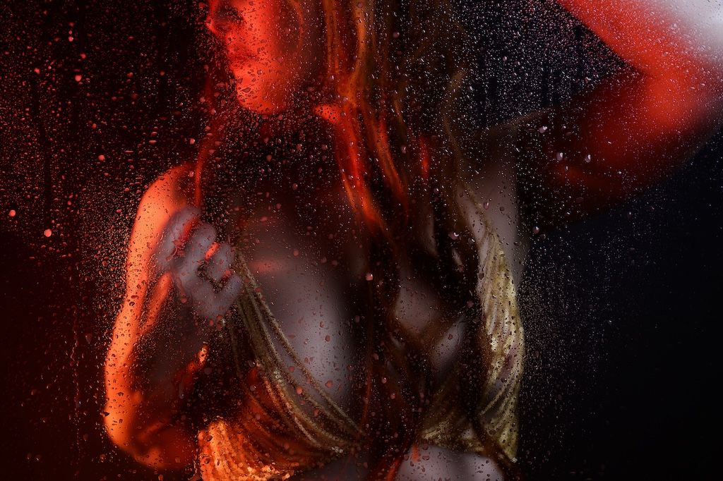 Gekleurd licht boudoirclose-up foto van een vrouw in glisterende top zeewolde