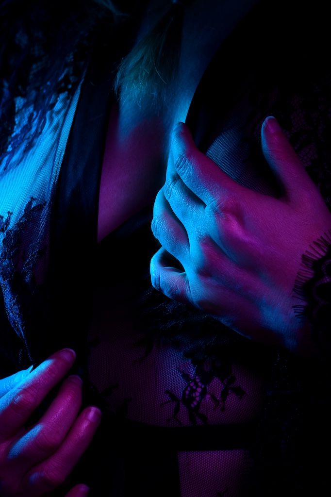 Close-up boudoirfoto van handen met blauwe verlichting bij een vrouw in zwarte kanten lingerie, in zeewolde