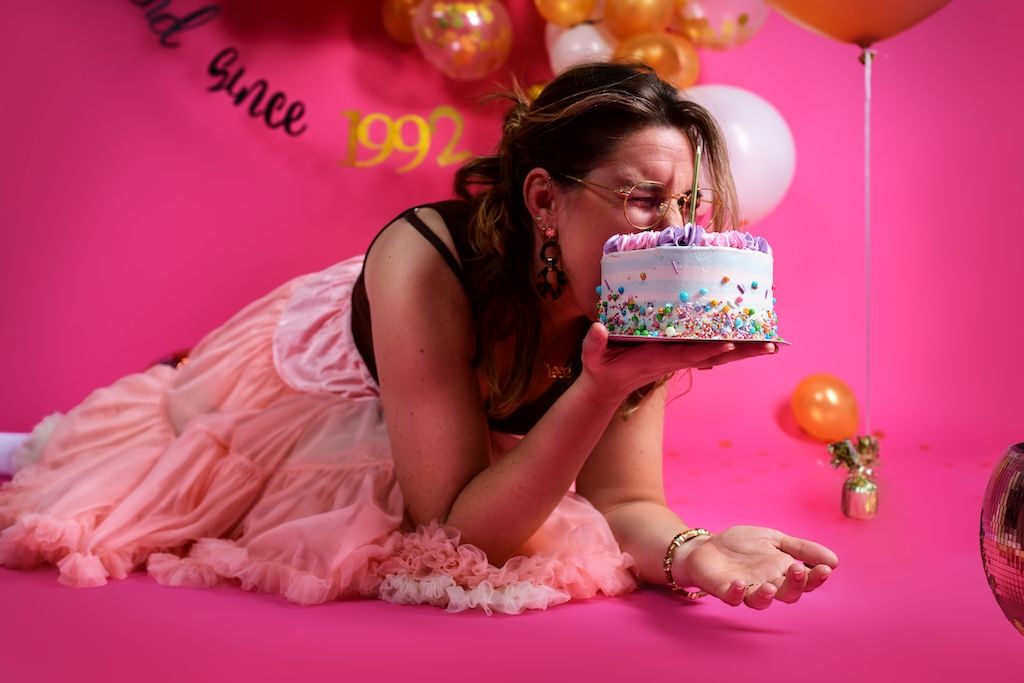 Cakesmash voor volwassenen in Zeewolde. Vrouw met gezicht in taart voor roze achtergrond