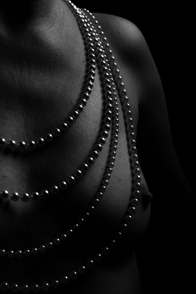 A series of black and white macro shots showing delicate pearl necklace details against dark shadows.