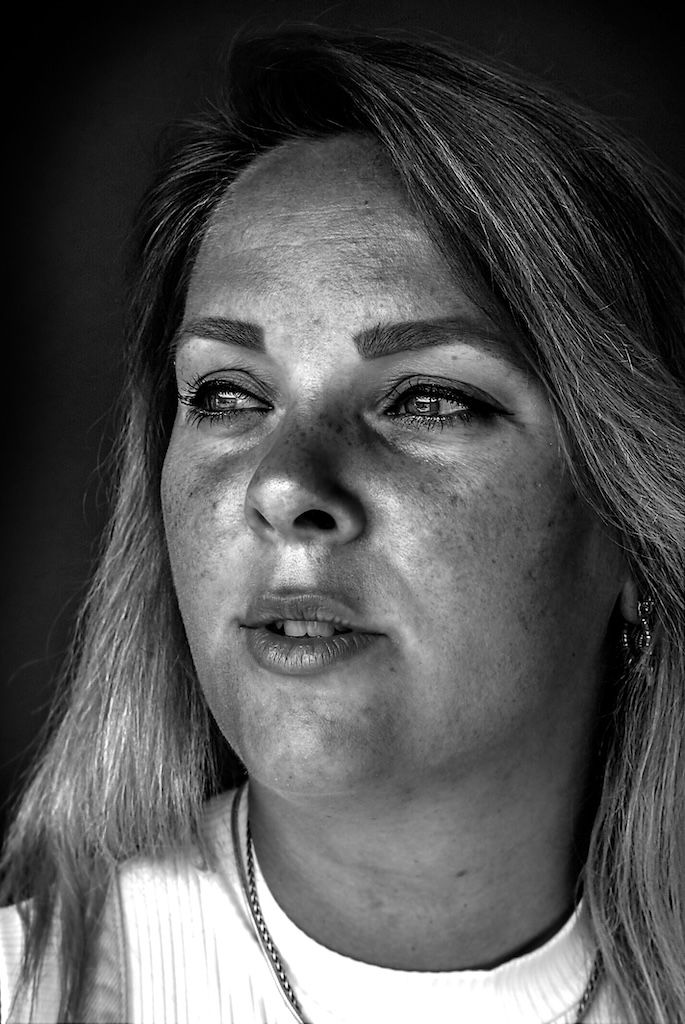 Zwart-wit close-upportret van een vrouw met lang haar, sproeten en een halsketting, die iets buiten beeld kijkt.