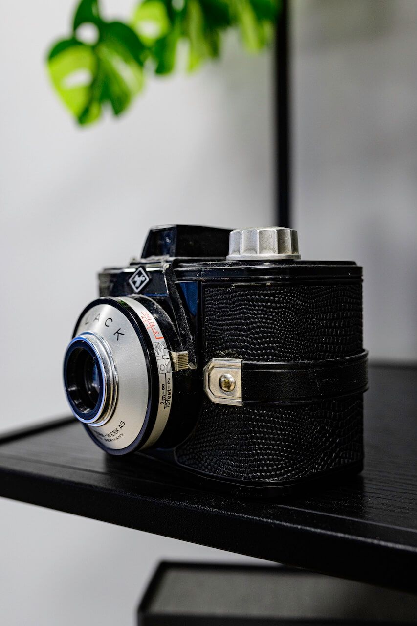 Een vintage camera van zwart, generfd leer met een zilverkleurige lens in daglichtstudio Zeewolde