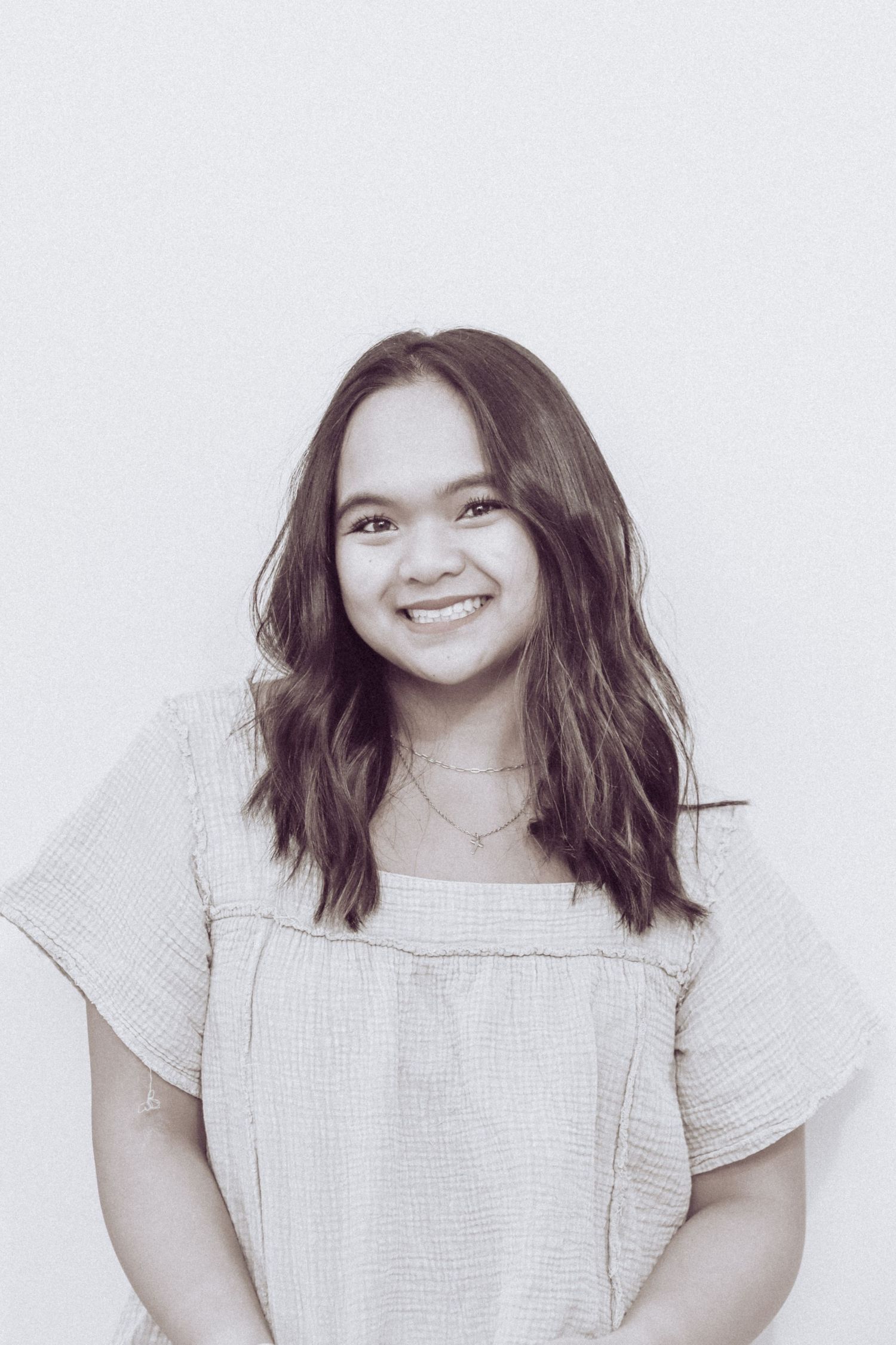 Studio portrait of someone in a light-colored casual top with a joyful expression.
