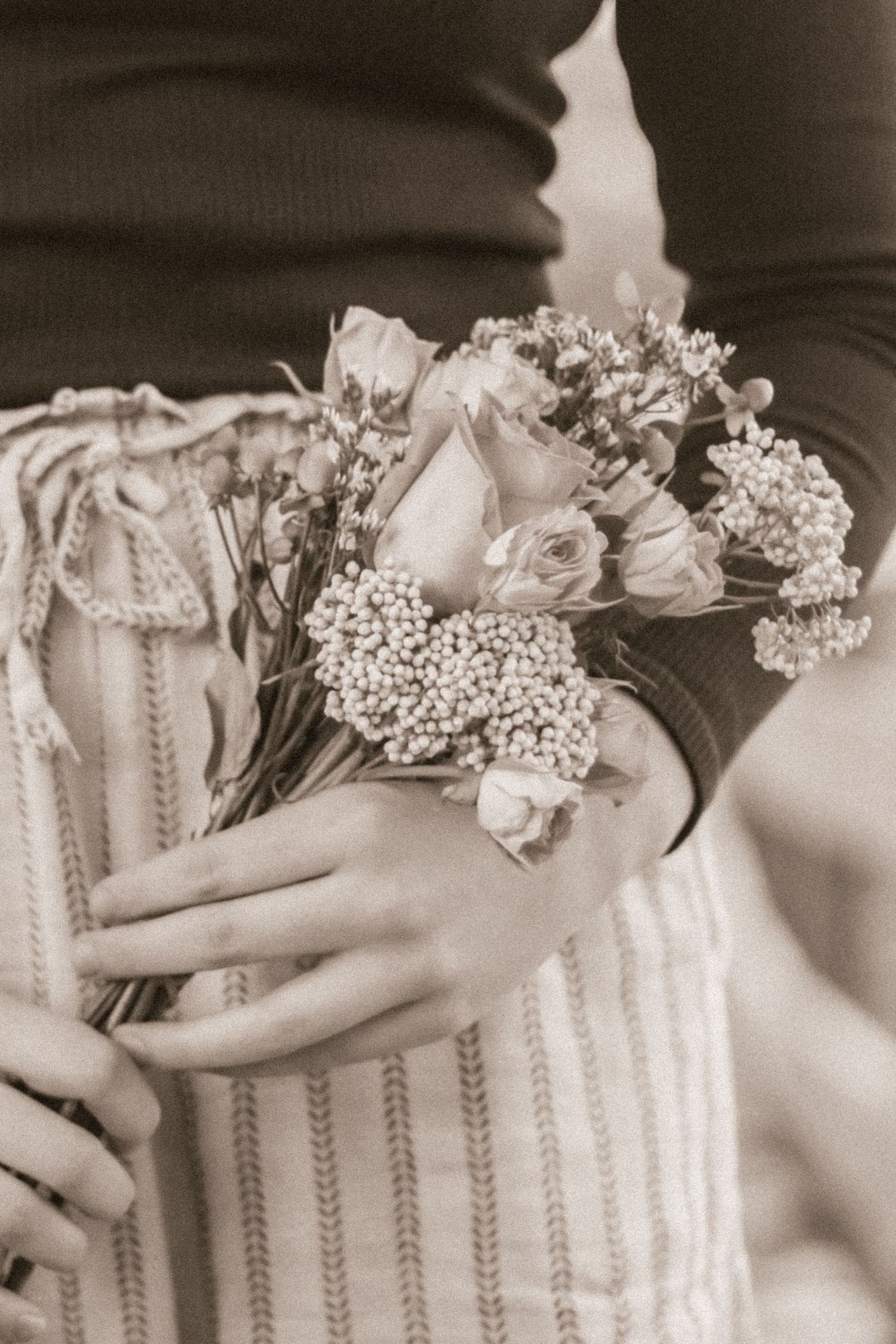 Delicate arrangement of baby's breath and roses against striped fabric in soft black and white.