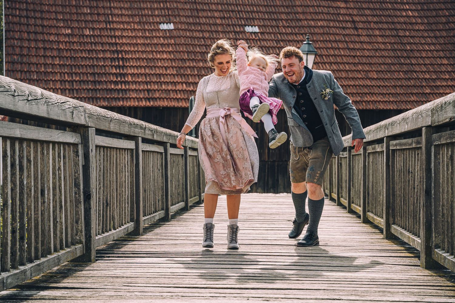 Standesamtliche Hochzeit in Neumarkt. Brautpaar mit Tochter in Tracht auf einer hölzernen Brücke.