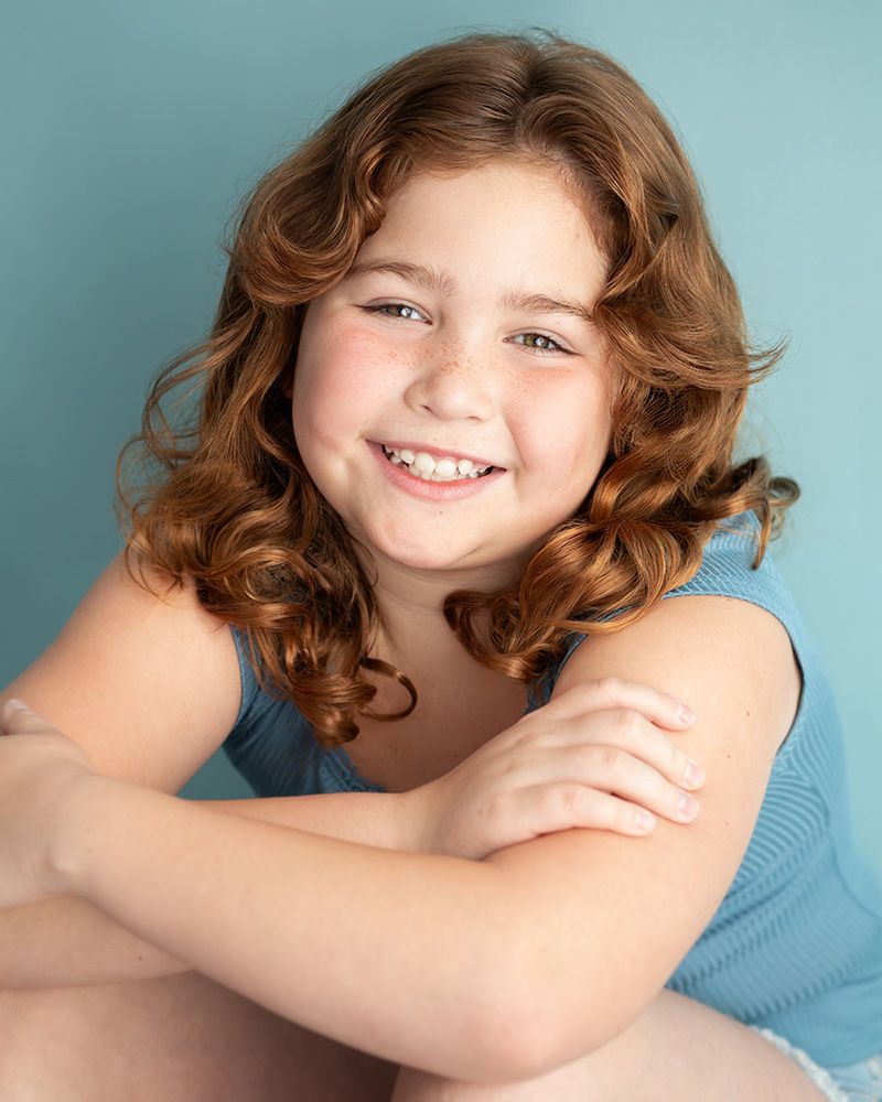 Young actor headshot for casting, clean natural lighting portrait, blue background