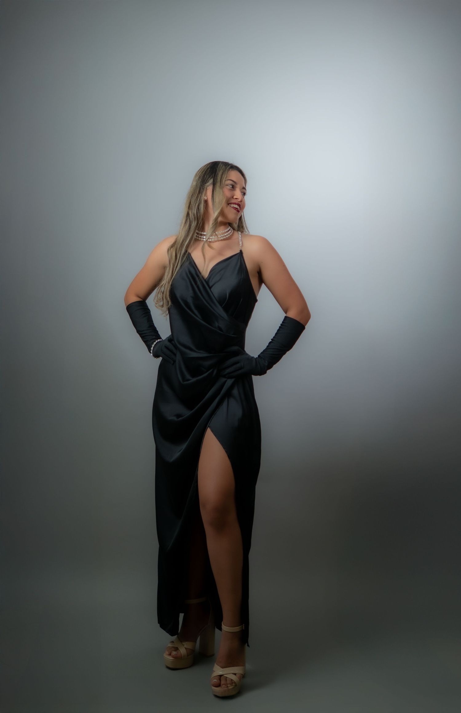 Woman in elegant black satin wrap dress with gloves and heels posing in studio. Guanacaste, Costa Rica