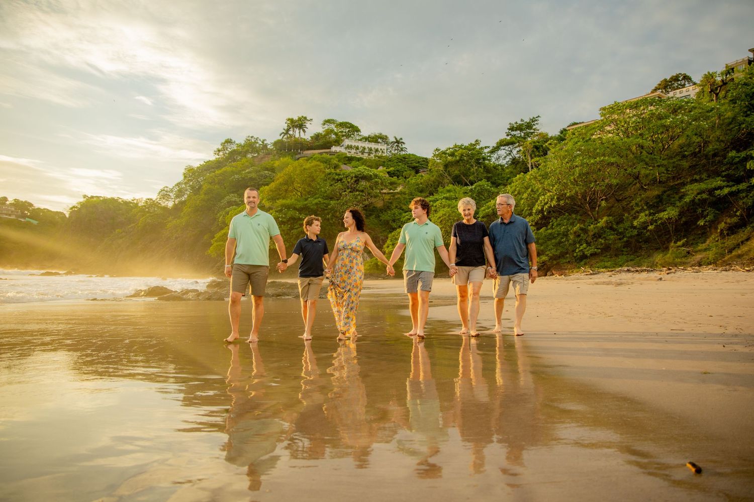 Six people holding hands walking along a scenic tropical beach at golden sunset hour. Guanacaste, Costa Rica