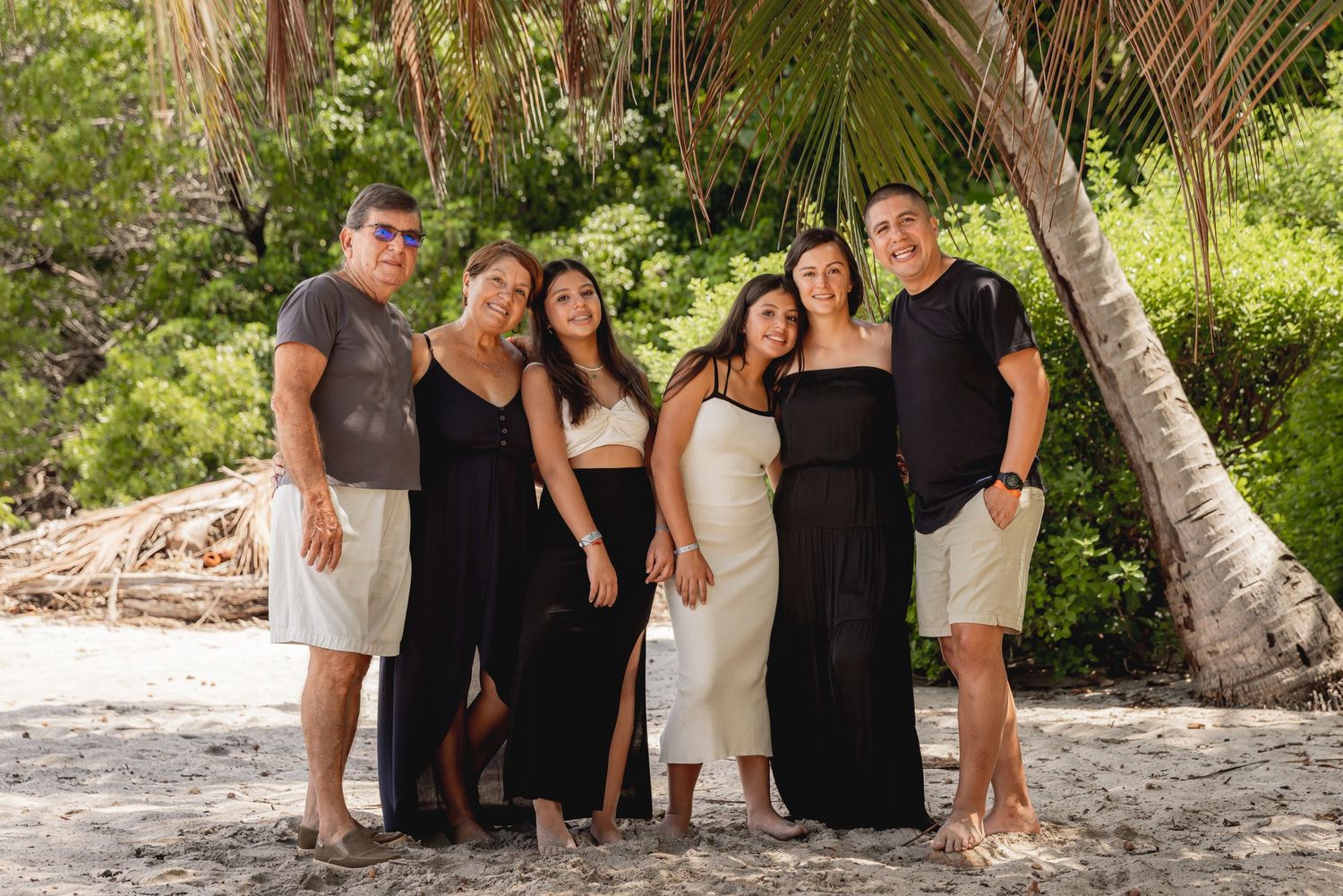 Family of six posing together on tropical beach wearing coordinated black and white outfits. Guanacaste, Costa Rica