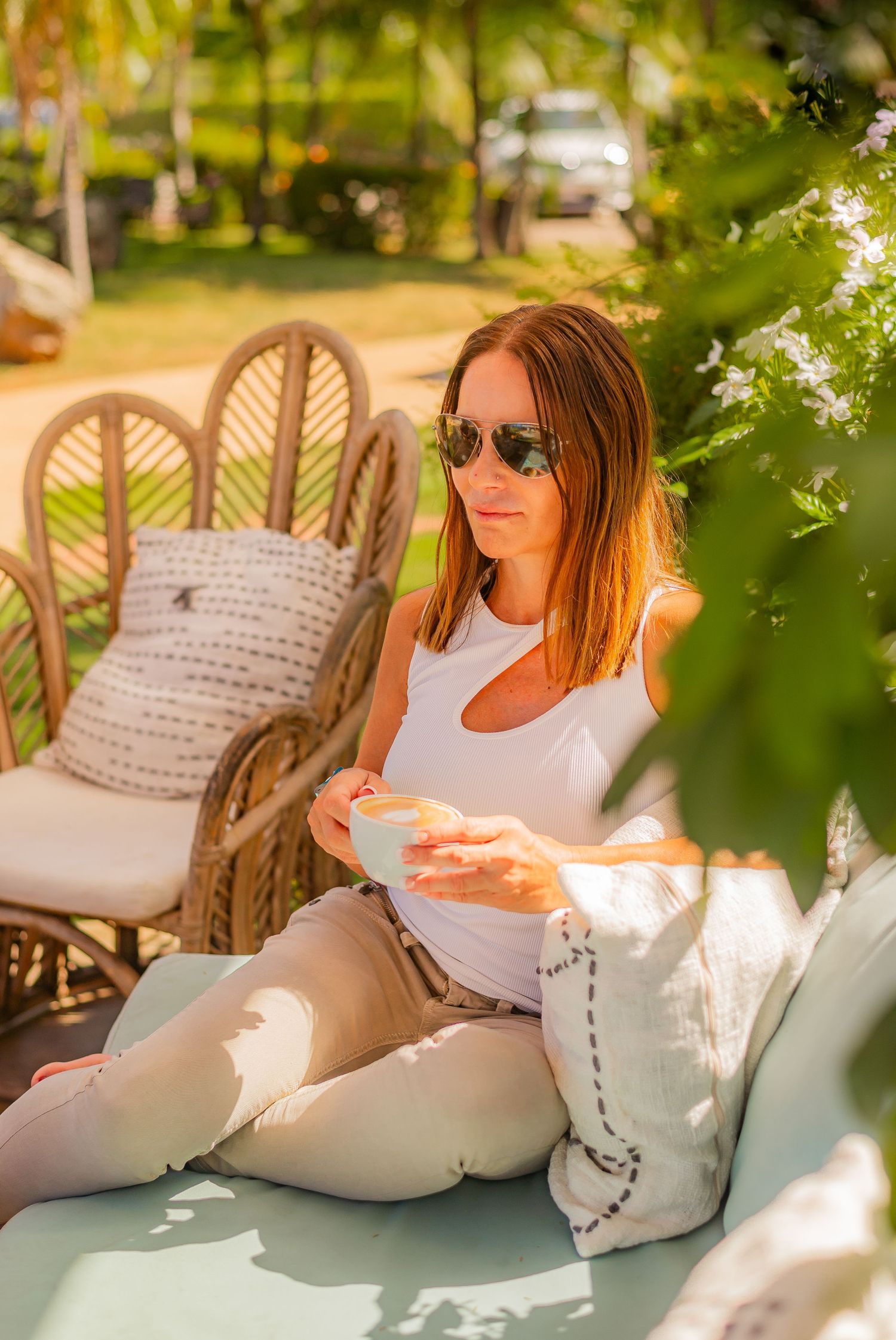Woman in sunglasses relaxing outdoors with coffee in a sunny tropical garden setting. Guanacaste, Costa Rica