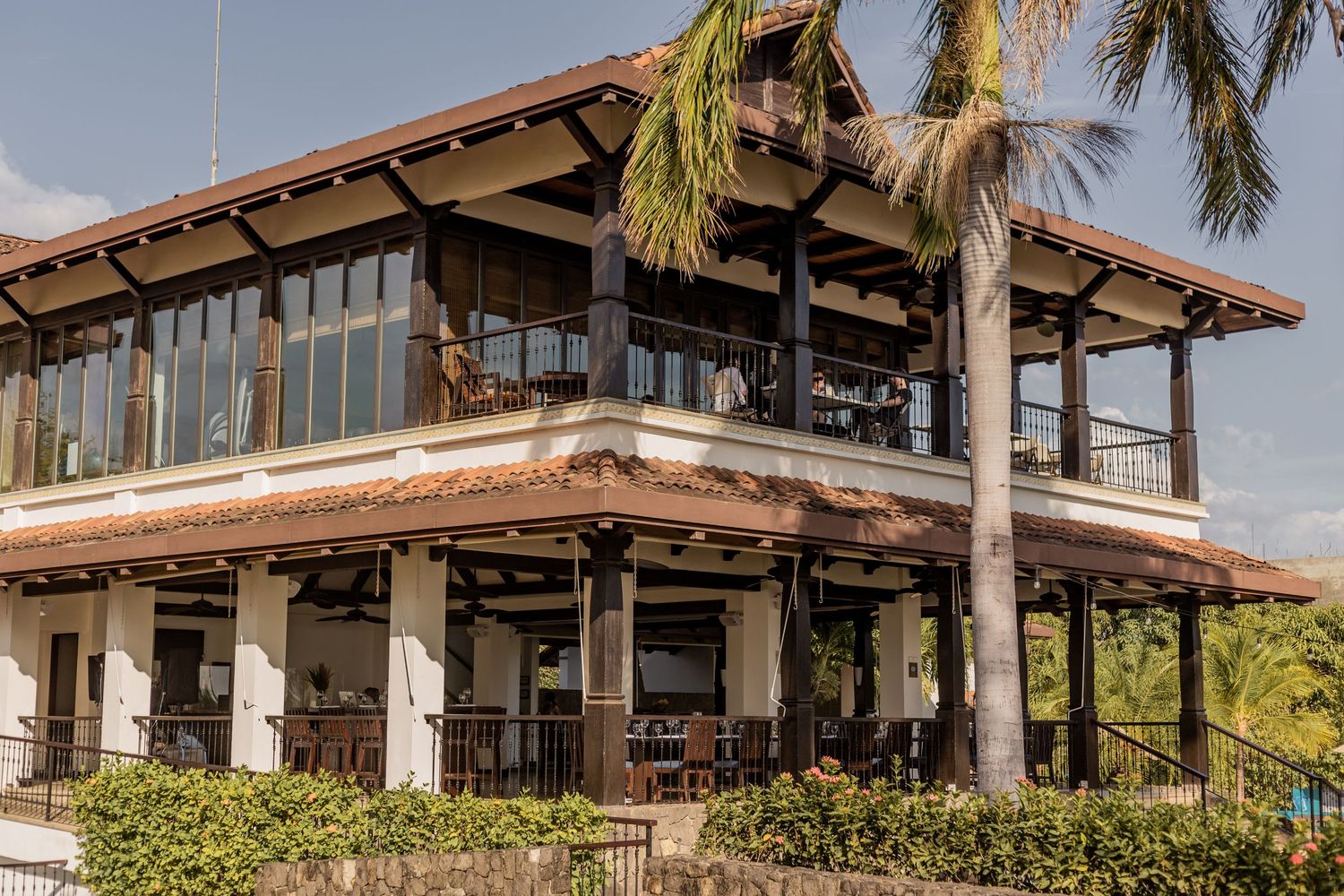 Tropical two-story restaurant building with large windows and palm trees. Guanacaste, Costa Rica