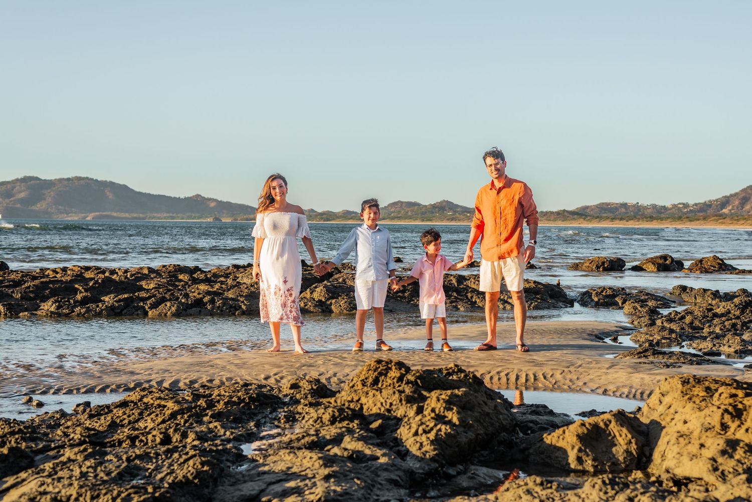 Family of four standing on rocky beach at golden hour. Guanacaste, Costa Rica