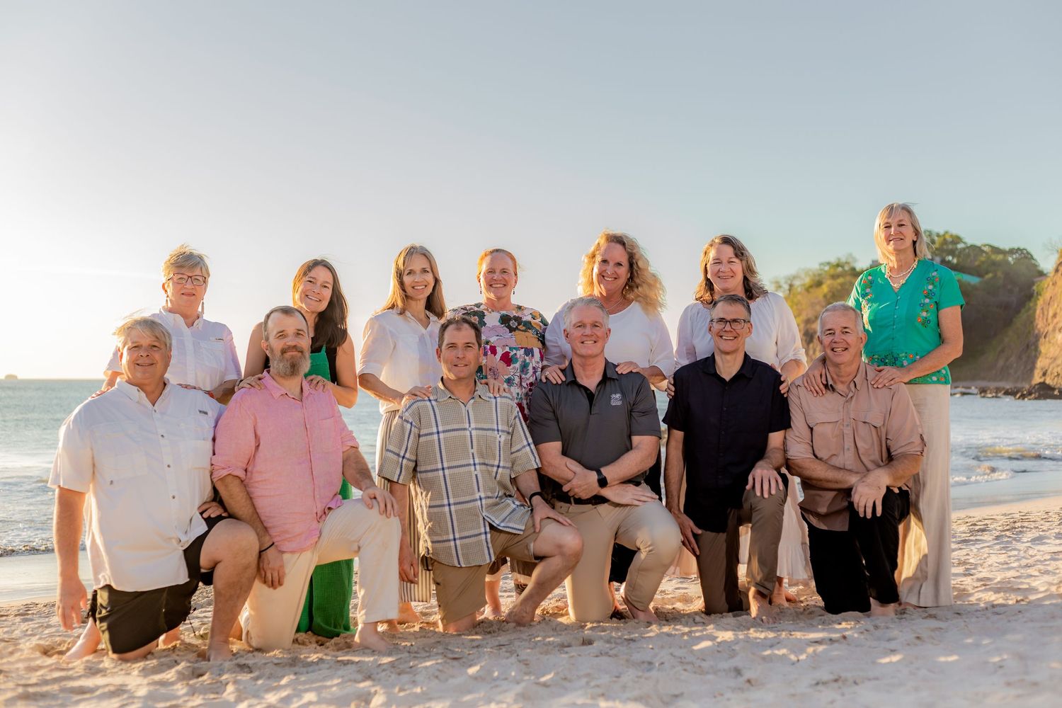 Group of adults posing together on a bright sandy beach for a team photo. Guanacaste, Costa Rica