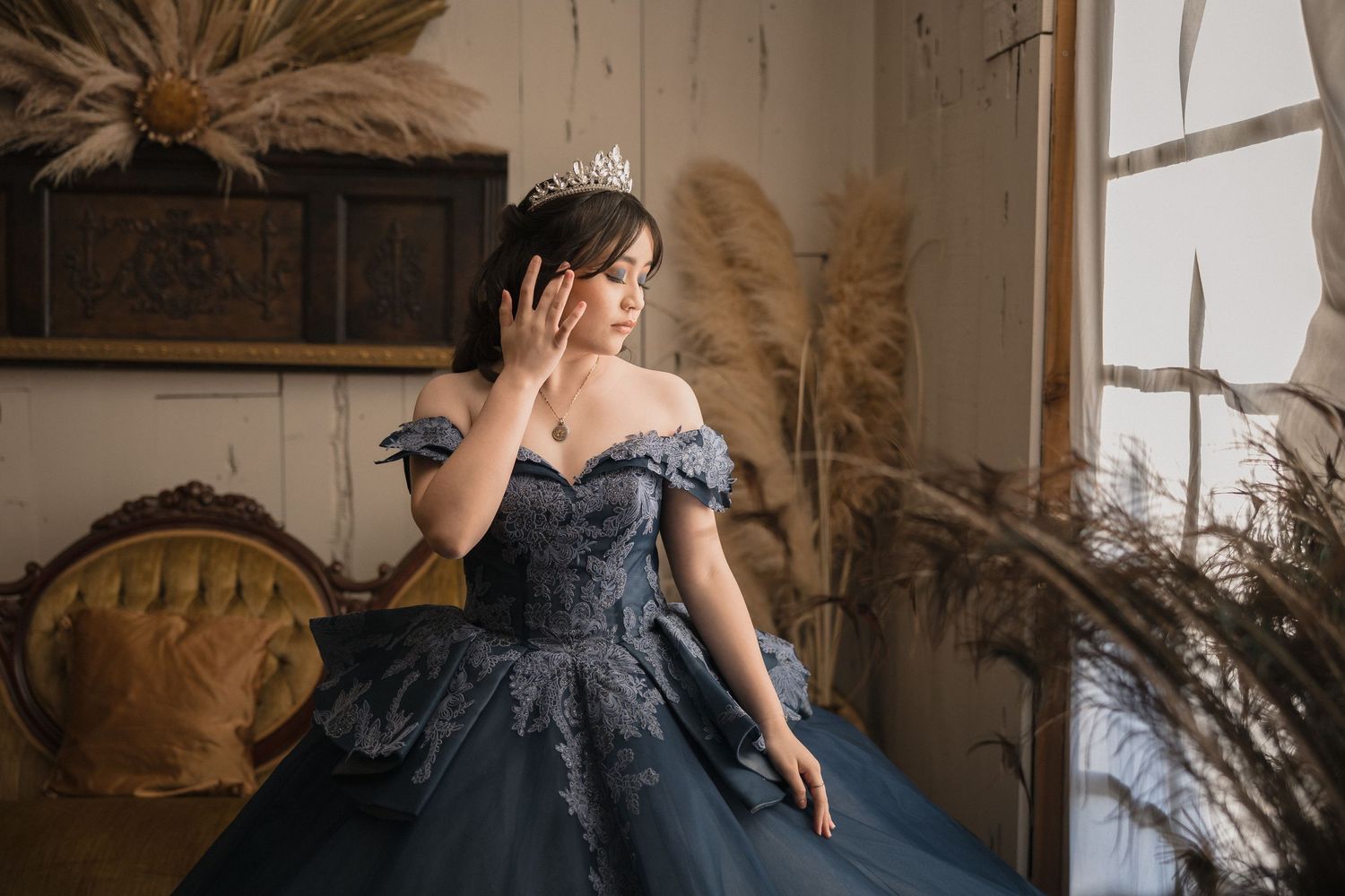 A dark blue off-shoulder quince dress in a vintage-styled room with antique boho style.