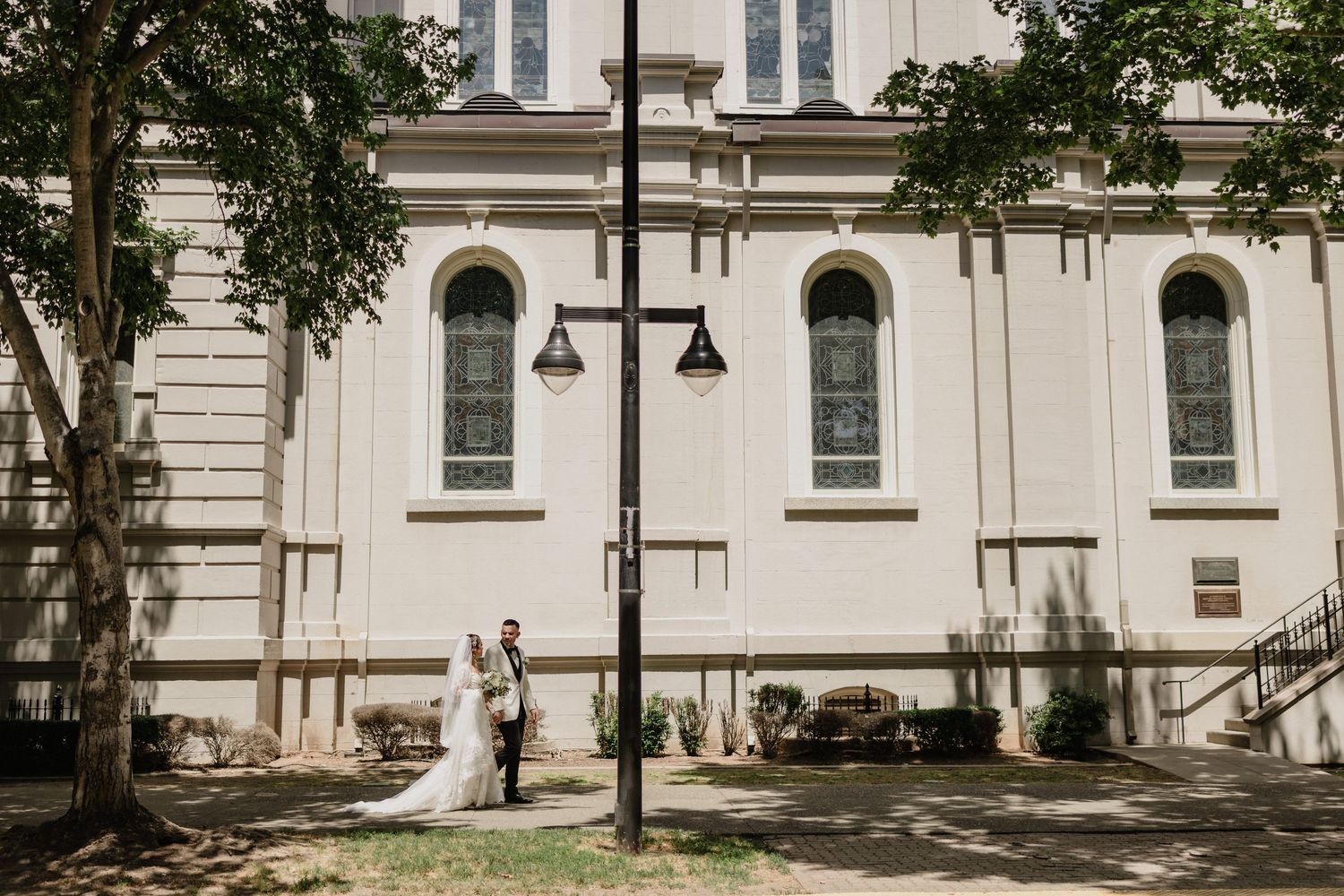 White classical building facade with tall windows and ornate architectural details surrounded by green trees for Sacramento wedding