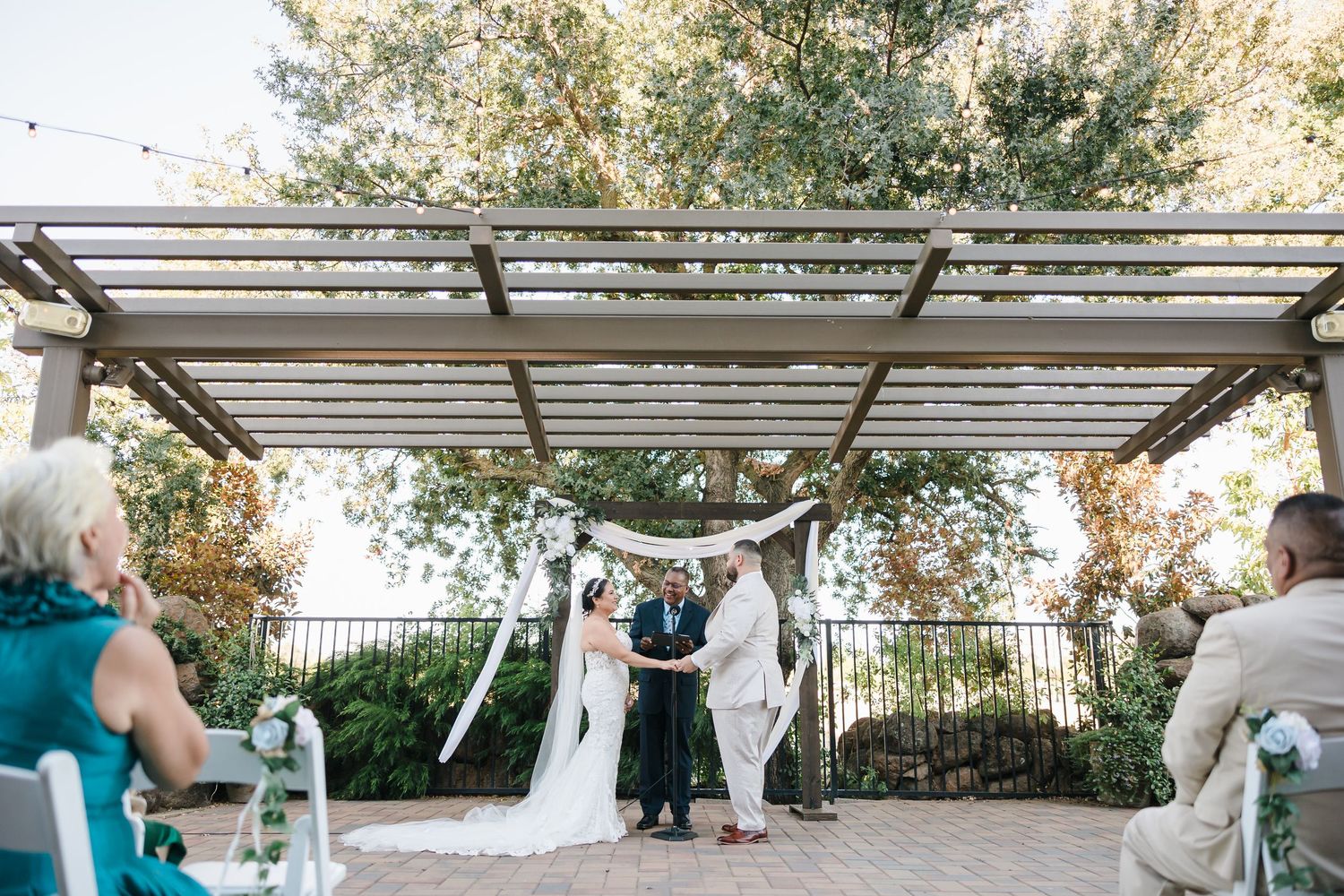 Wedding guests gather under an elegant covered outdoor patio during a celebration event.