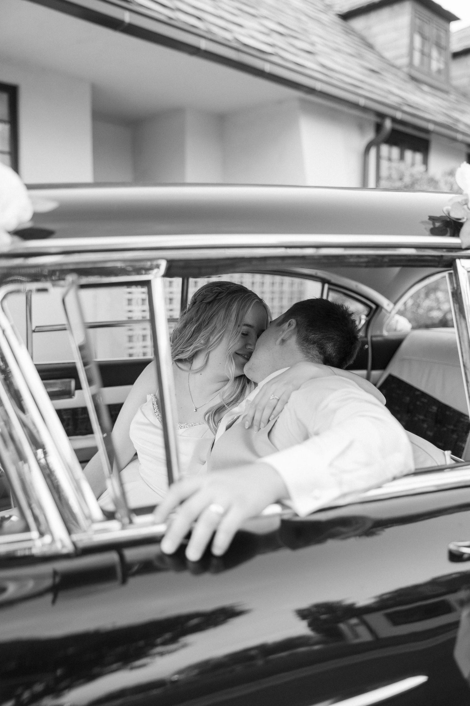 A black and white photo series showing different angles of people kissing in a vintage car.