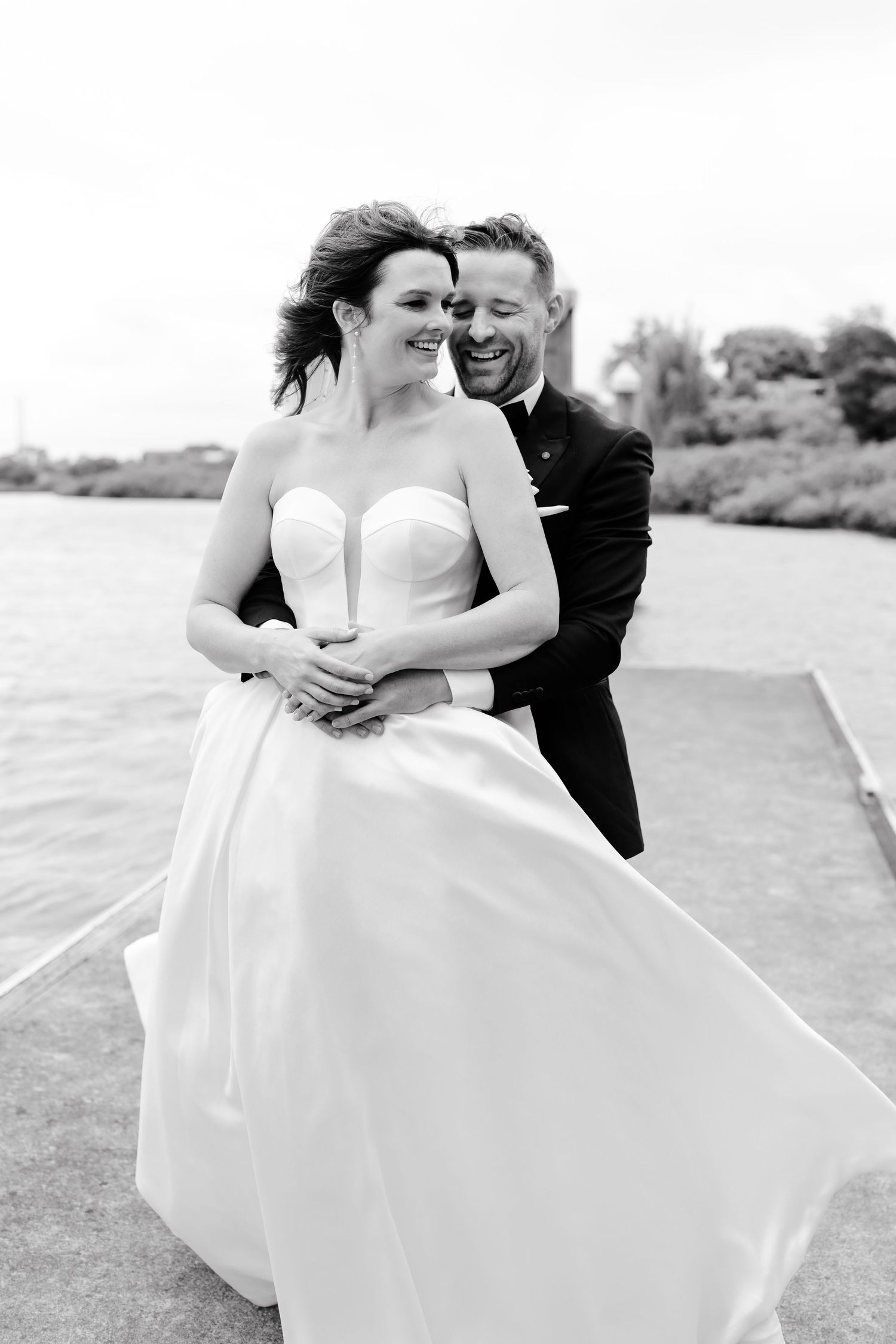 A romantic black and white wedding photo series showing a couple embracing outdoors in formal attire.