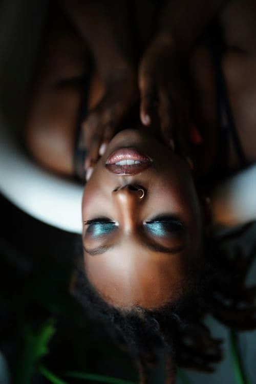 Close-up artistic beauty shots showing metallic eyeshadow and face jewelry details in dark lighting.