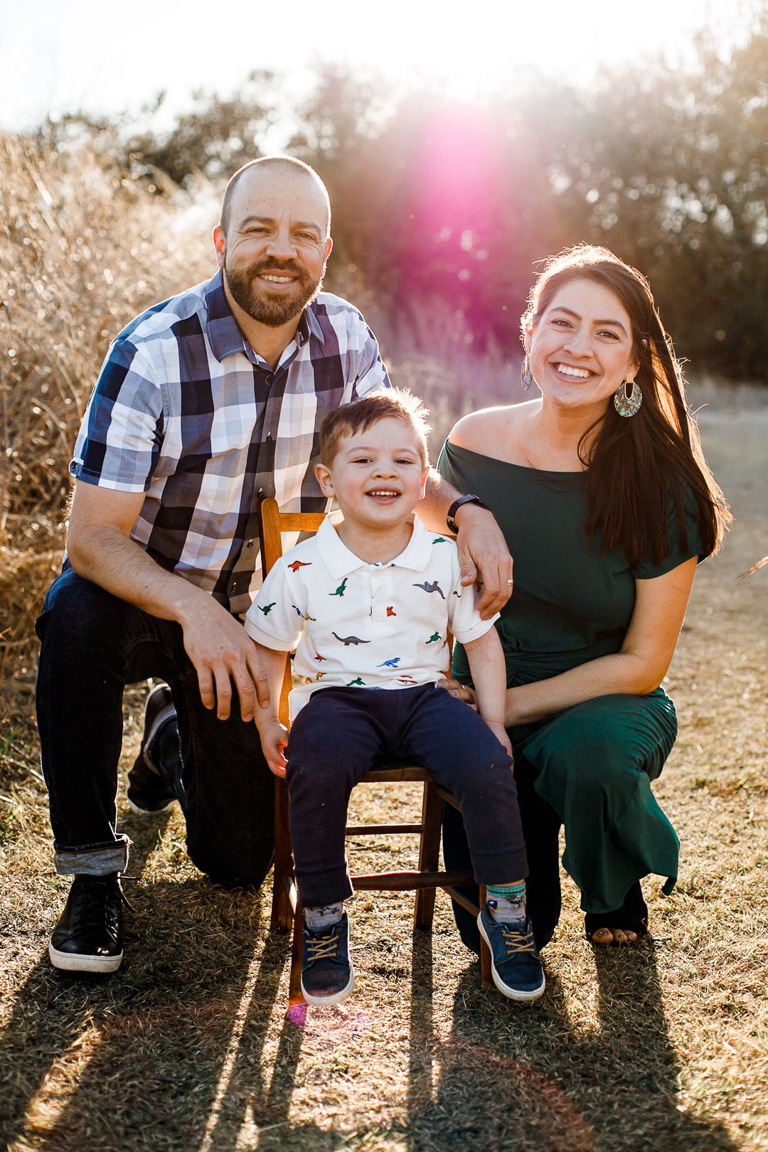 A happy family portrait of a father, mother, and young son smiling together outdoors in a scenic setting in Cedar Park during family photos