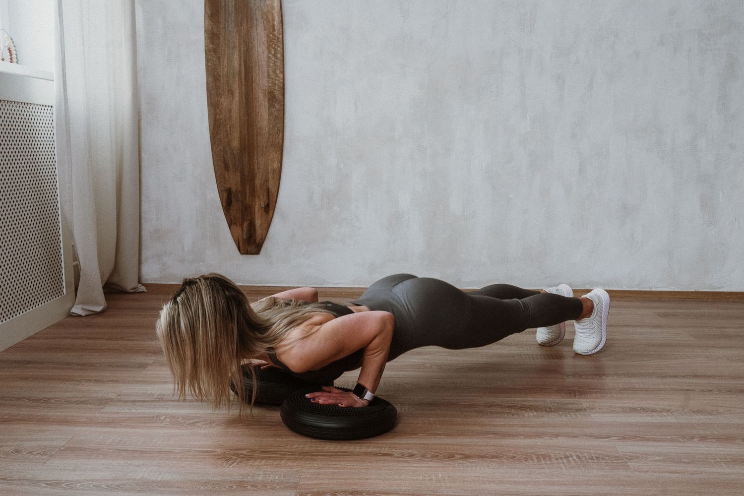 Athletic person performs a push-up on a weightlifting plate during indoor workout session.