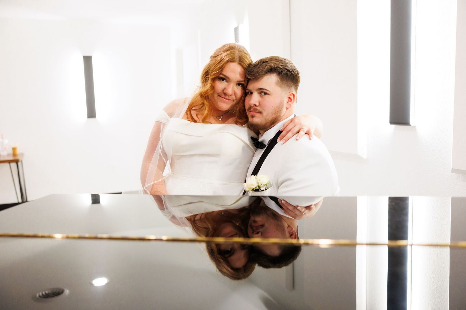 A bride and groom pose together while their reflection shows in a polished surface below at Venue at Shadow Rock in Branson, Missouri.