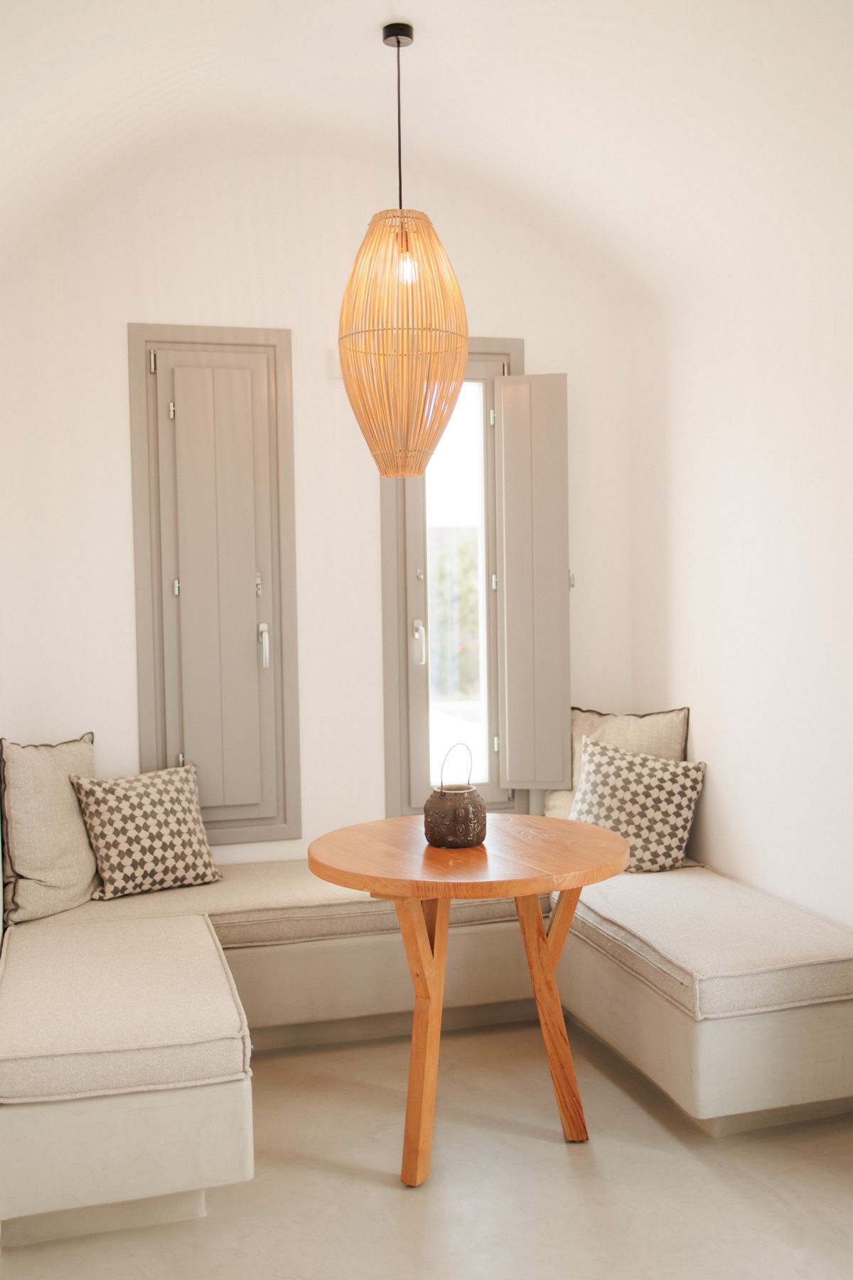 Bright minimalist room with wicker pendant lamp, round wooden table, and built-in bench seating.