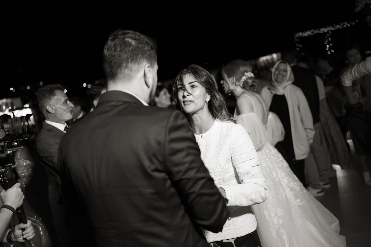 Bride and guest share intimate dance moment at elegant black and white wedding reception.