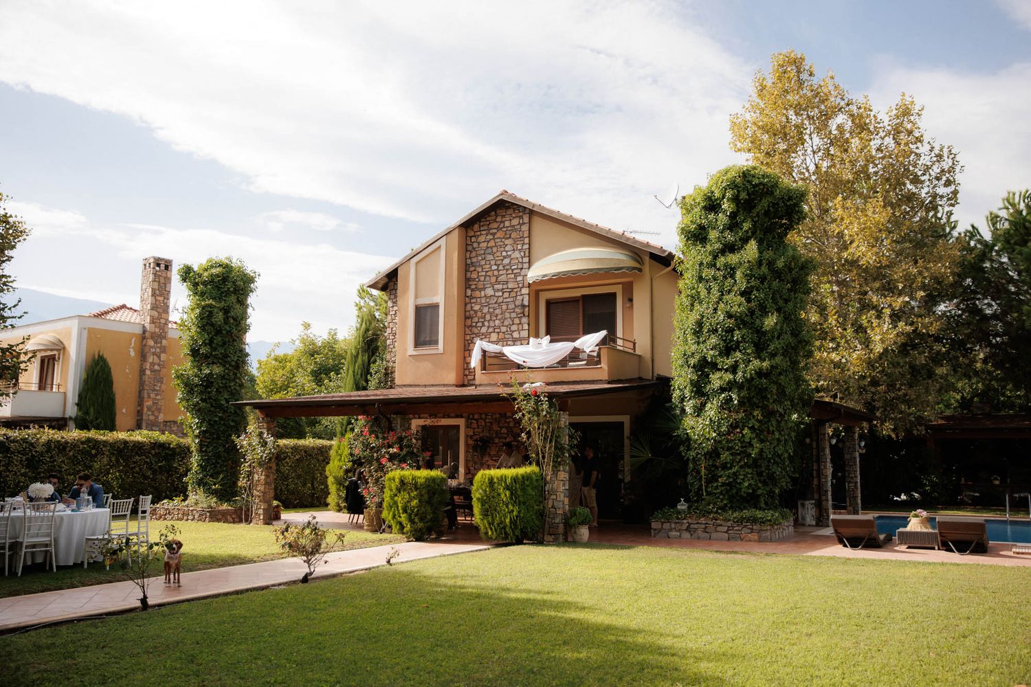 Elegant wedding venue with stone and wood architecture surrounded by lush greenery and manicured lawns.