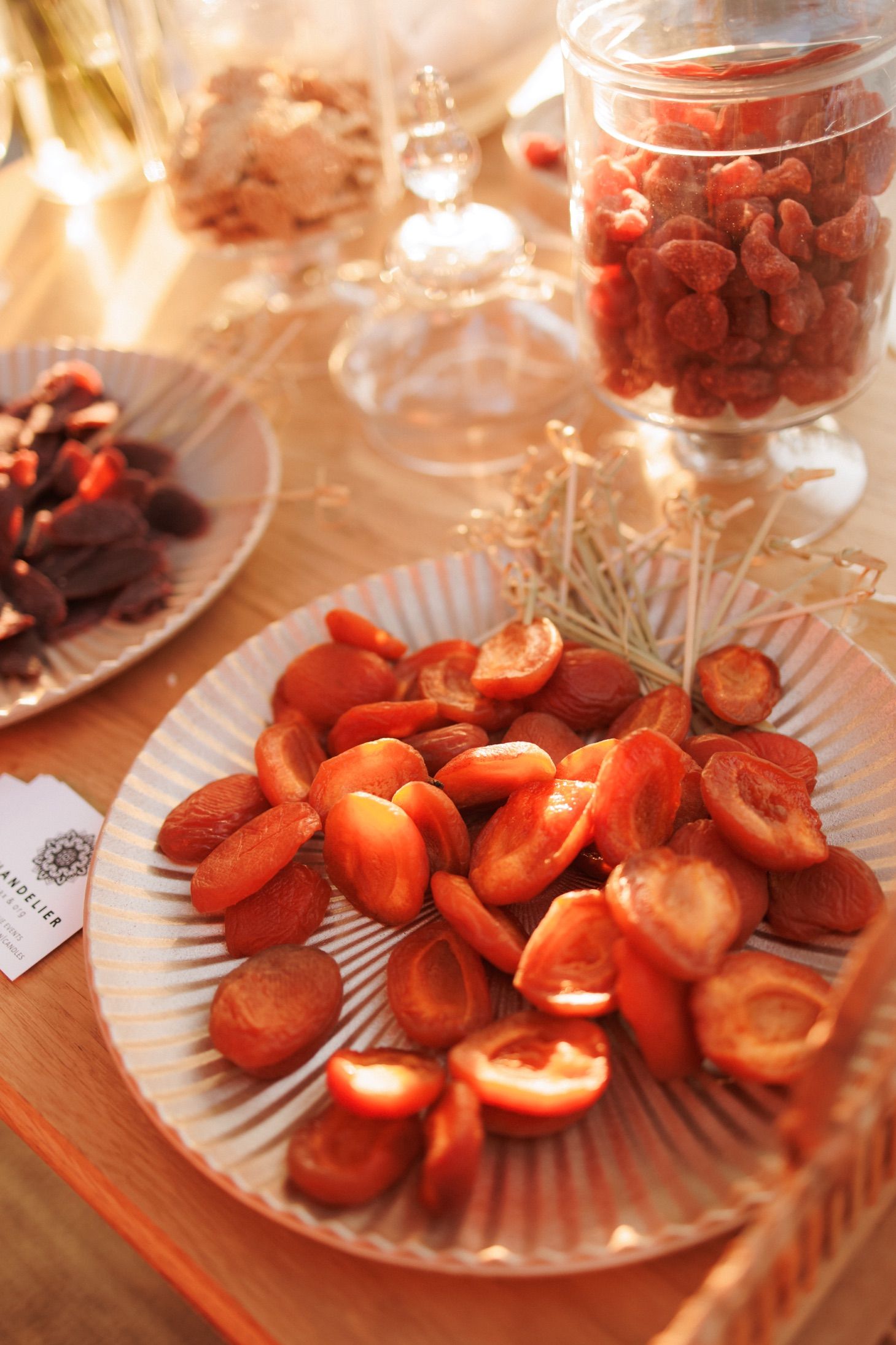 Dried apricots and red berries displayed on decorative plates at an outdoor wedding dessert table.