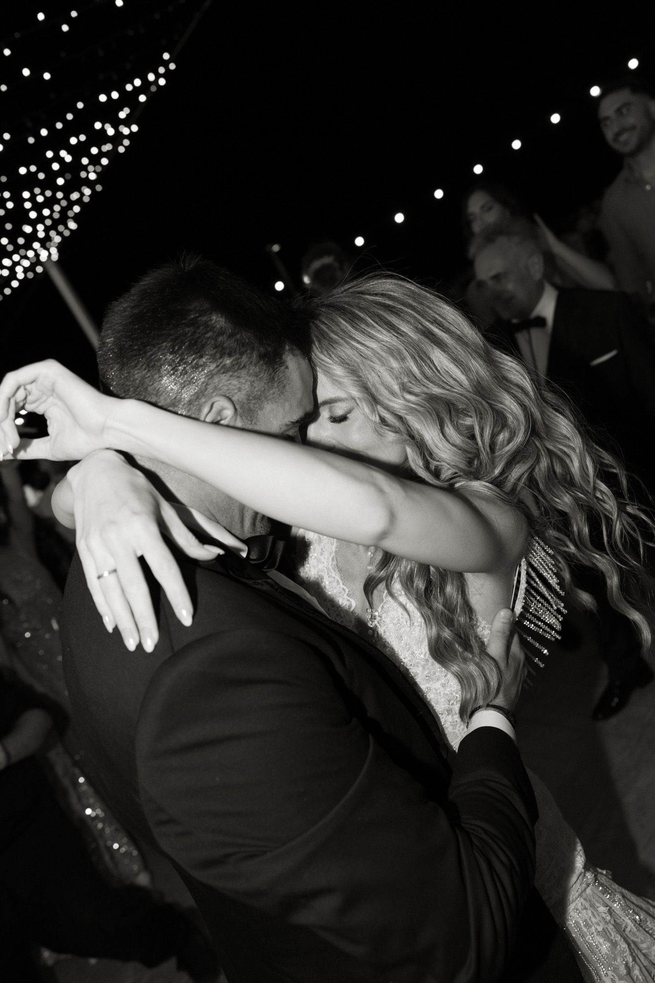 Black and white romantic embrace of bride and groom during intimate first dance at wedding reception.
