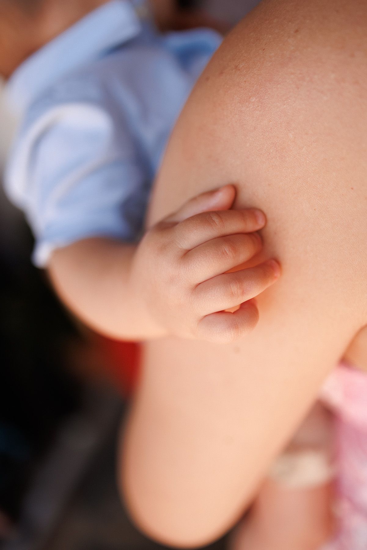 Close-up of a tiny baby hand gently resting on an adult's arm, captured in soft natural light.