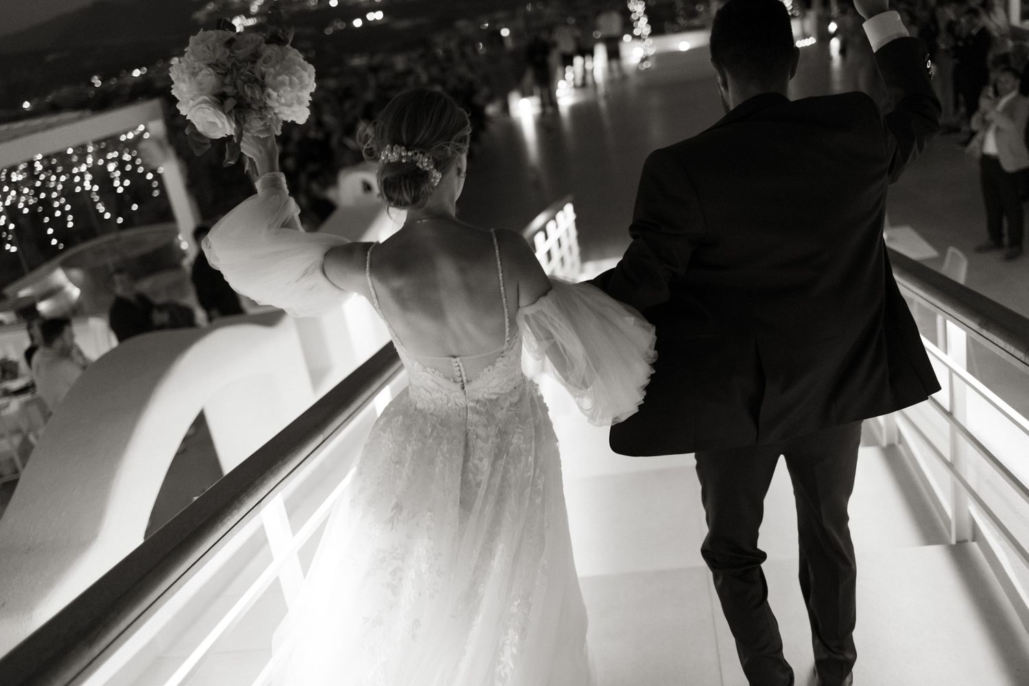 Bride and groom walking up stairs at elegant wedding reception in black and white photography.