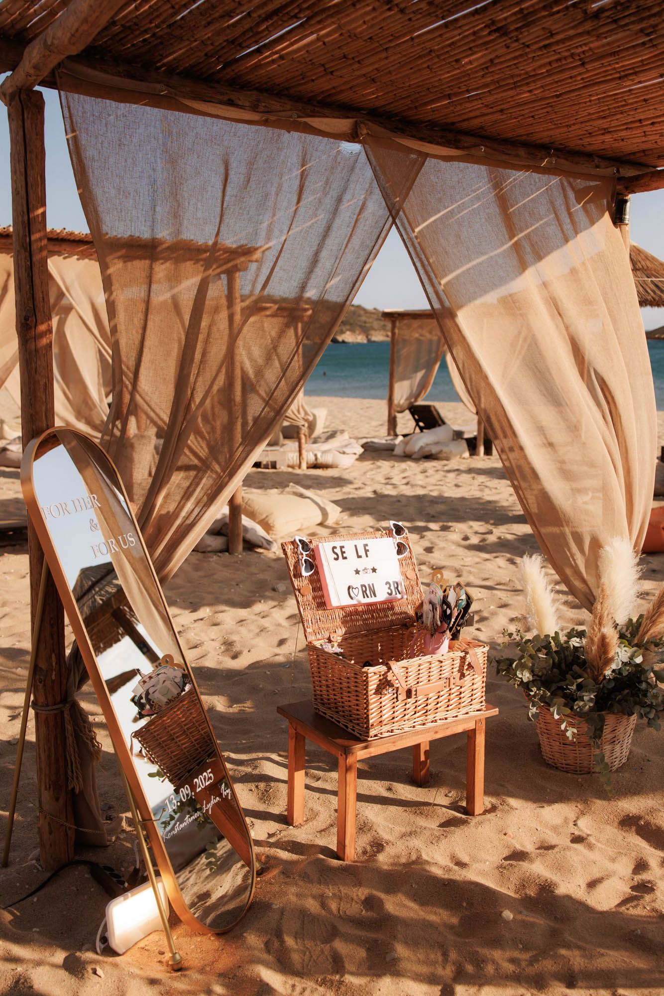Beach selfie corner station with wicker basket and props under rustic canopy.