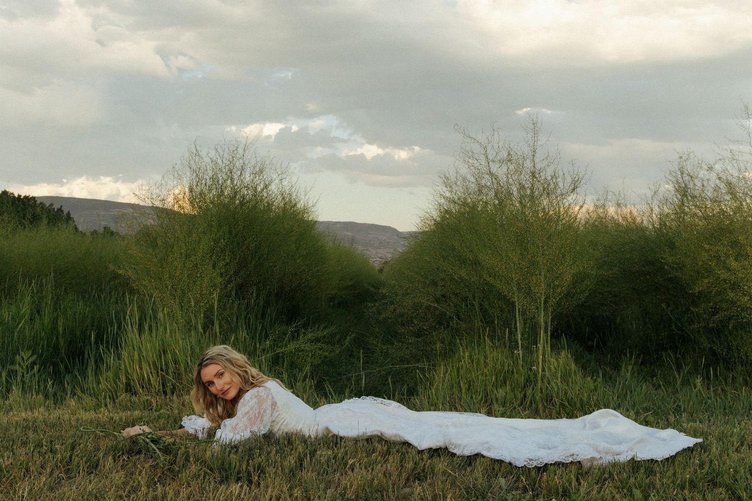 Creative bridal portrait of a bride lying in a field in Utah.”