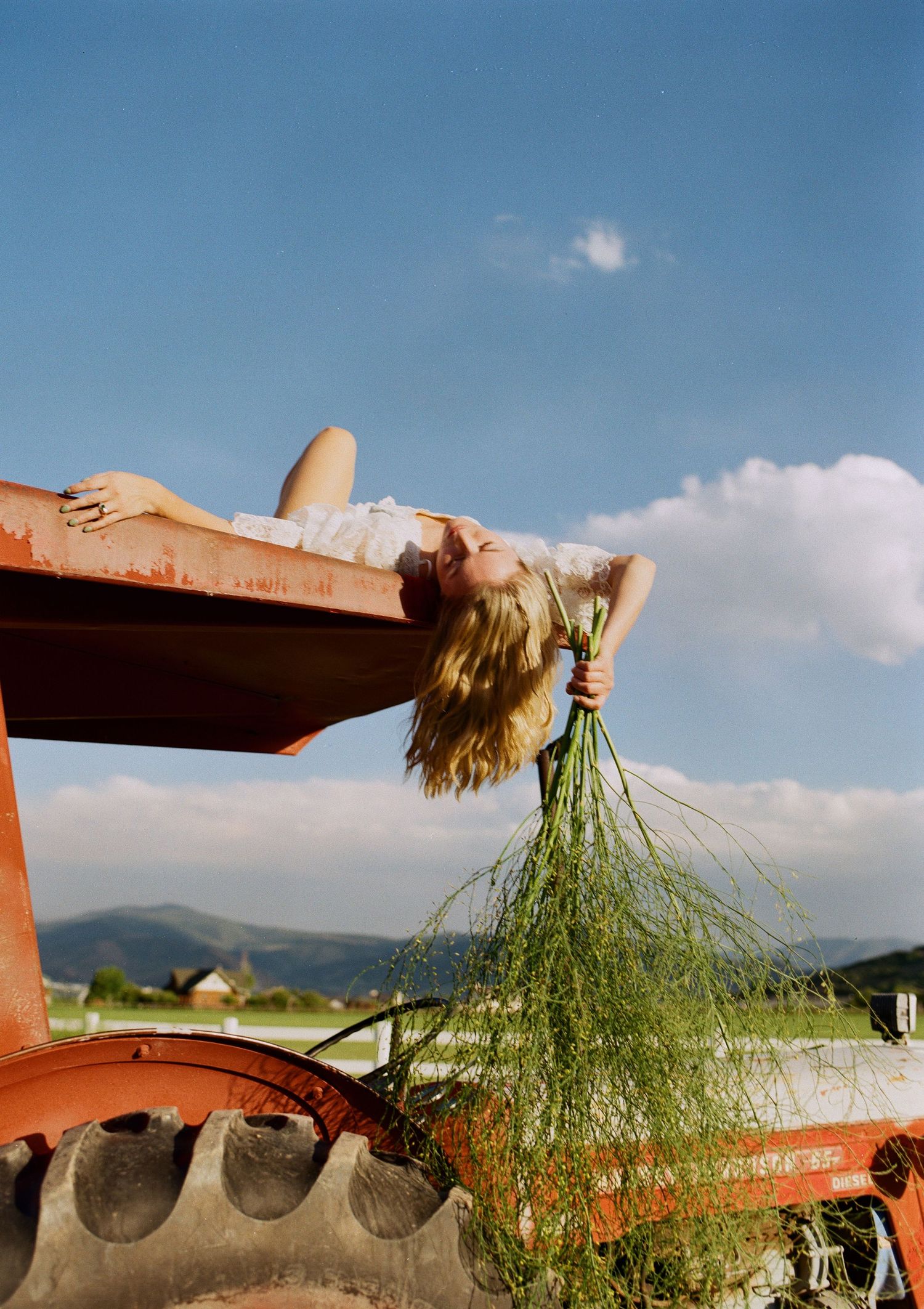 Creative 35mm film bridal portrait on a vintage tractor in the Utah countryside.
