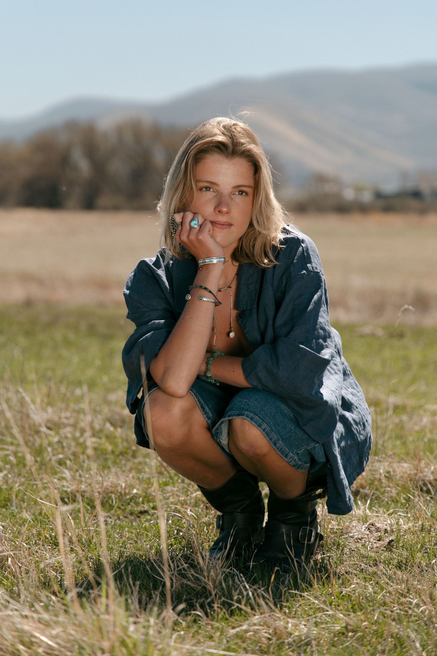 Editorial outdoor portrait of a woman in a field with Utah mountains in the background.
