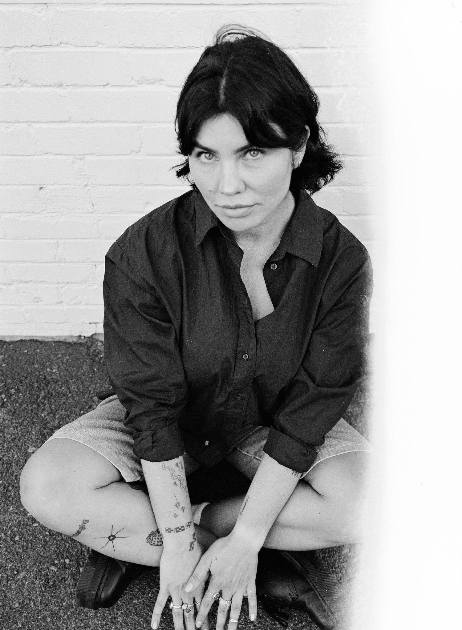 Black and white 35mm film portrait against a white brick wall in Salt Lake City, Utah.
