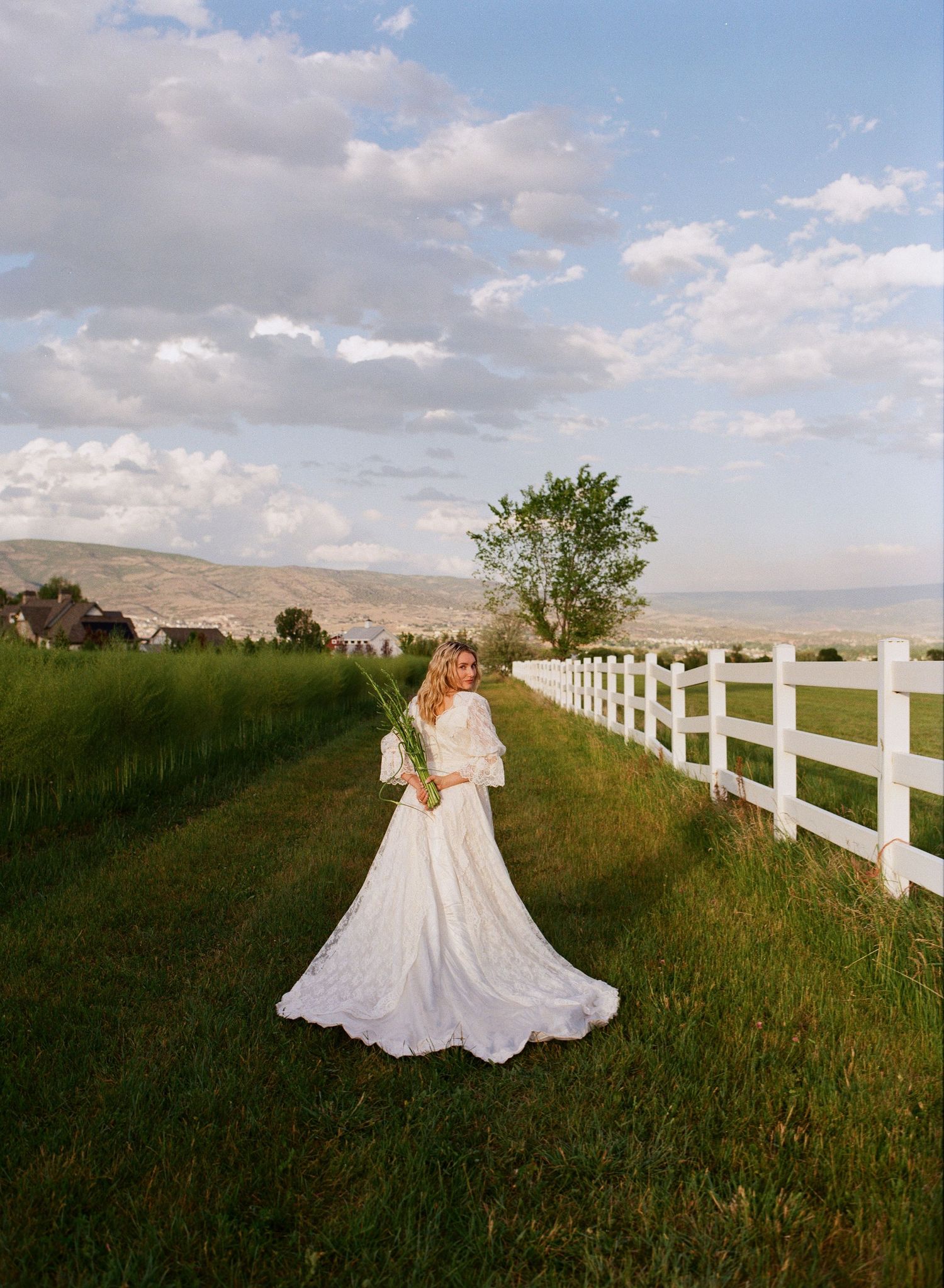 35mm film bridal portrait beside a white fence in the Utah countryside.