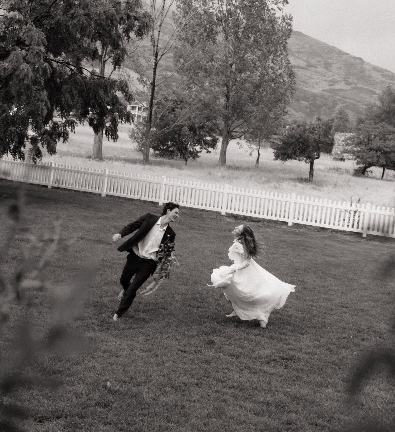 Bride and groom running through a field at their Salt Lake City, Utah wedding.