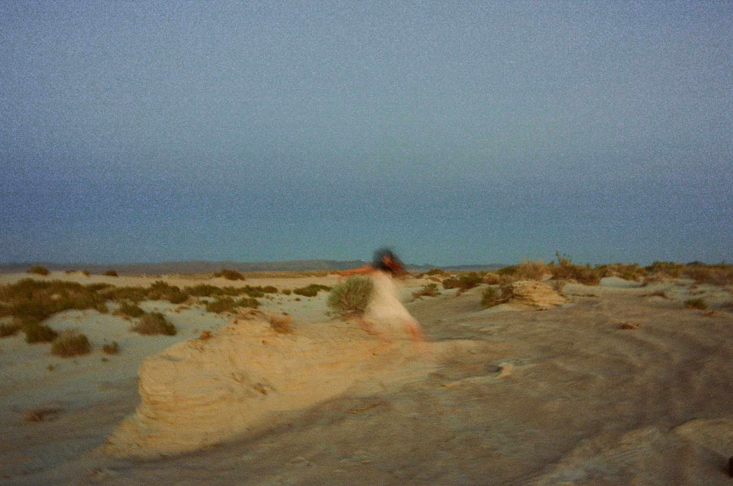 Dreamy 35mm film portrait of a woman moving through a desert landscape in Utah.
